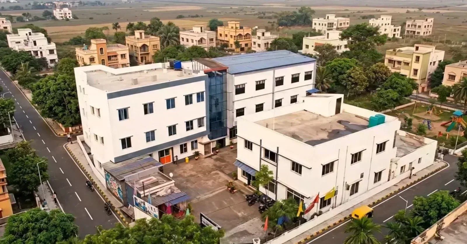 Aerial view of the School of Hospitality & Management campus at Rajbandh, Durgapur, showing both academic blocks, the courtyard between them and the approach road