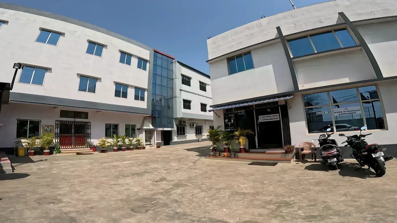 The front courtyard of School of Hospitality & Management, Durgapur, with the Block B entrance on the right and the academic block on the left