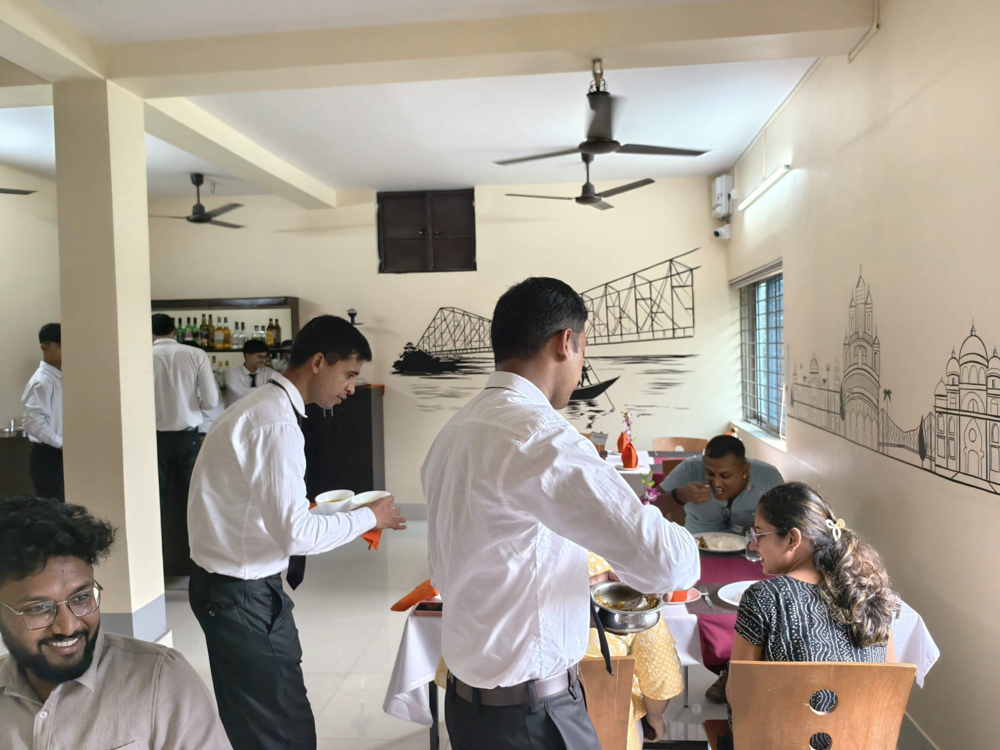 Hotel management students in service uniform waiting on guests in the training restaurant at School of Hospitality & Management, Durgapur
